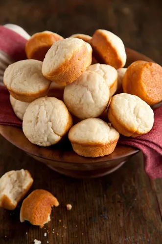 Paula Deen easy rolls piled in a wooden bowl on a red cloth with a few broken rolls in front