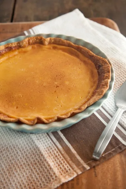 Paula Deen eggnog custard pie with a golden nutmeg-dusted top and crimped crust in a pale blue scalloped pie plate