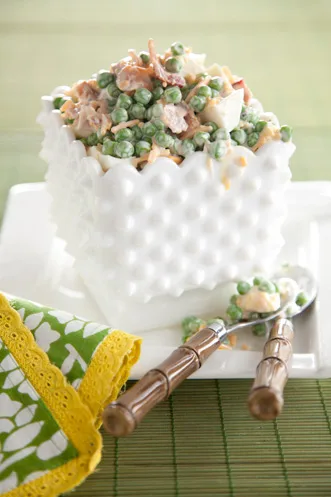 Paula Deen English pea salad with green peas, bacon, cheddar and chopped egg in a white milk glass bowl