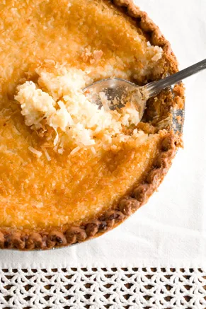 Paula Deen French coconut pie with a golden toasted coconut top and a spoon lifting out a creamy slice