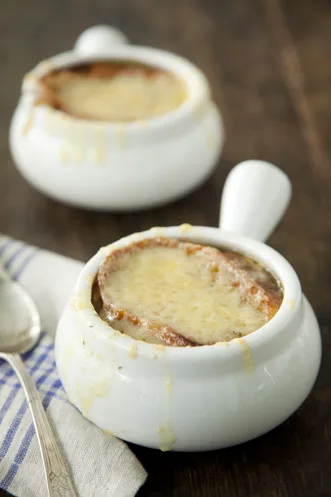 Paula Deen French onion soup in white ovenproof bowls topped with browned melted Gruyere cheese over toasted bread