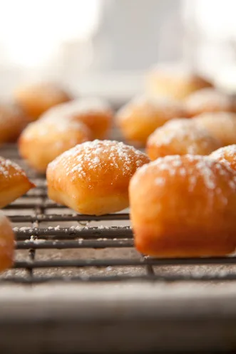 Paula Deen French Quarter beignets dusted with confectioners' sugar cooling on a wire rack