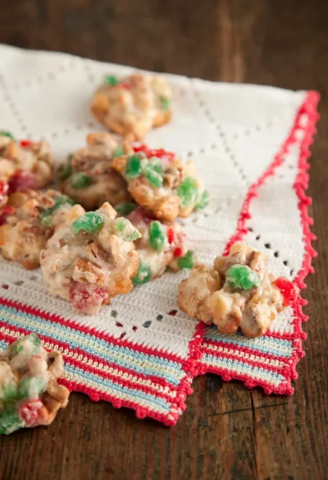 Paula Deen fruitcake drop cookies studded with red and green candied cherries and pecans on a white crocheted towel