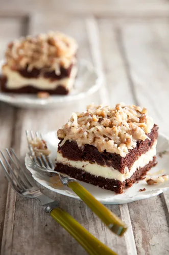 Paula Deen German chocolate cake cheesecake style square with a creamy cheesecake layer and coconut pecan frosting on a white plate