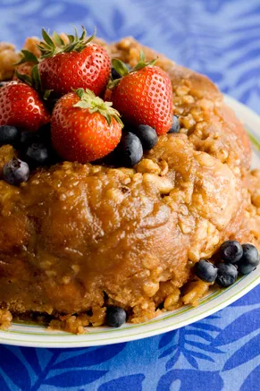 Paula Deen gorilla bread bundt topped with fresh strawberries and blueberries on a floral plate