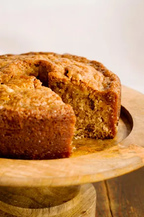 Paula Deen Grandgirl's Fresh Apple Cake from Georgia on a wooden cake stand with one slice cut out