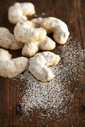 Paula Deen Grandma Paul's sand tarts, crescent-shaped pecan cookies dusted with confectioner's sugar on a wooden table