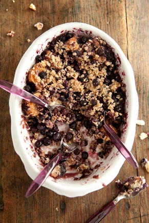 Paula Deen Granite Steps country blueberry coffee cake in an oval white baking dish topped with oats and blueberries, with purple spoons