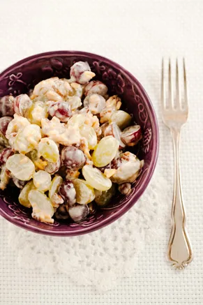 Paula Deen grape salad with red and green grapes in a creamy dressing with pecans in a purple bowl beside a fork