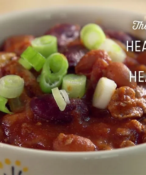 Paula Deen healthy chili in a white bowl with ground turkey, kidney beans and sliced green onions on top