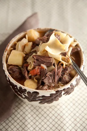 Paula Deen hearty beef and noodle soup with tender short rib meat, parsnips and wide egg noodles in a decorative bowl