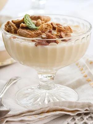 Paula Deen honey pudding in a glass dessert cup topped with crushed honey graham crackers, honey-roasted peanuts and a fresh mint leaf