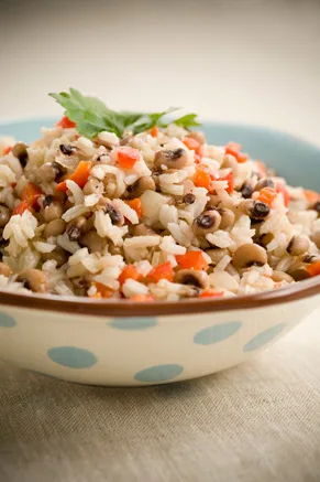 Paula Deen Hoppin' John in a blue polka dot bowl with black eyed peas, rice, diced red bell pepper and a parsley sprig