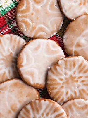Paula Deen iced gingerbread cookies with patterned tops and a glossy white glaze on a red plaid cloth