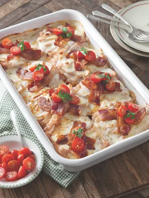 Paula Deen Kentucky Hot Brown Casserole in a white baking dish topped with bacon, chopped tomatoes and parsley