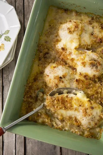 Paula Deen Lady and Sons' chicken in wine sauce baked in a green casserole dish with melted Swiss cheese and golden stuffing topping