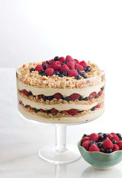Paula Deen lemon berry trifle layered with cheesecake filling, wafer crumbs, raspberries and blueberries in a glass trifle bowl