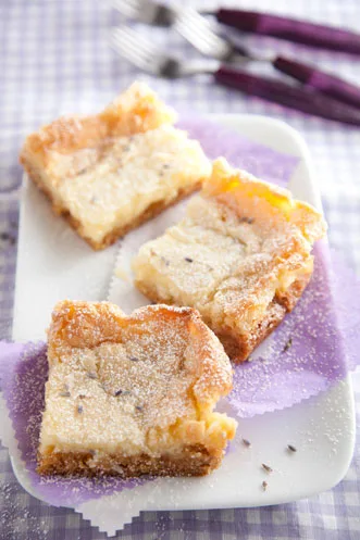 Paula Deen lemon lavender gooey butter cake squares dusted with powdered sugar on a white plate with purple paper