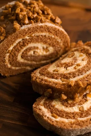 Paula Deen lighter pumpkin roll cake sliced to show the spiced pumpkin sponge spiral with toffee bit whipped filling