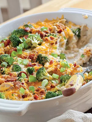 Paula Deen loaded baked potato casserole with broccoli, chicken, bacon, melted cheddar and green onion in a white baking dish