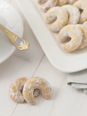 Paula Deen Mexican wedding cookies shaped as crescents and dusted with confectioners' sugar on a white platter