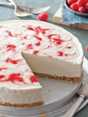 Paula Deen no-bake raspberry swirl cheesecake with a slice cut out, showing the graham cracker crust and red raspberry swirls on top