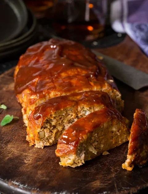 Paula Deen old-fashioned meat loaf sliced on a wooden board with a glossy ketchup glaze