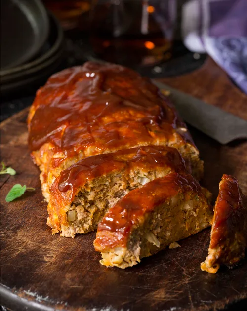 Paula Deen old-fashioned meat loaf sliced on a wooden board with a glossy ketchup glaze
