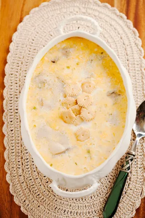 Paula Deen oyster stew in a white oval dish, creamy milk broth with oysters and oyster crackers on top
