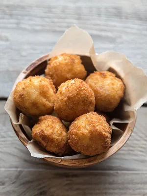 Paula Deen Paula's fried butter balls piled golden brown in a wooden bowl lined with parchment paper