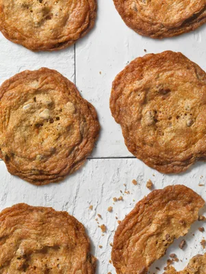 Paula Deen thin and crispy chocolate chip cookies with golden brown lacy edges on a white wooden surface