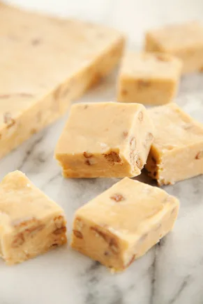 Paula Deen peanut butter cheese fudge cut into squares with chopped nuts on a white marble surface