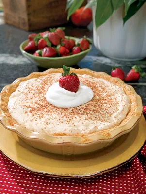 Paula Deen peanut butter pie in a yellow pie plate topped with grated chocolate, whipped cream and a fresh strawberry