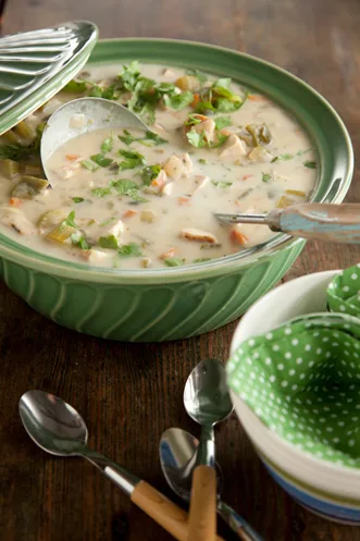 Paula Deen poblano chicken chowder in a green serving bowl with a ladle, topped with fresh cilantro