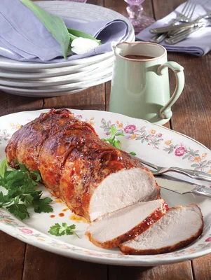 Paula Deen pork loin with bourbon-cola sauce sliced on a floral platter with fresh parsley