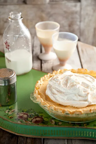 Paula Deen pumpkin chiffon pie topped with whipped topping and cinnamon in a golden crust next to glasses of milk