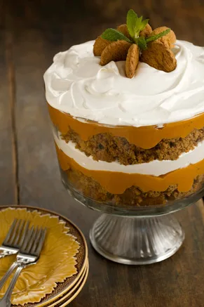 Paula Deen pumpkin gingerbread trifle in a footed glass bowl with layers of gingerbread, pumpkin pudding and whipped topping, garnished with gingersnaps and mint