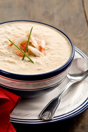 Paula Deen quick crab stew in a navy-rimmed white bowl topped with crab meat and chives, with a silver spoon beside it