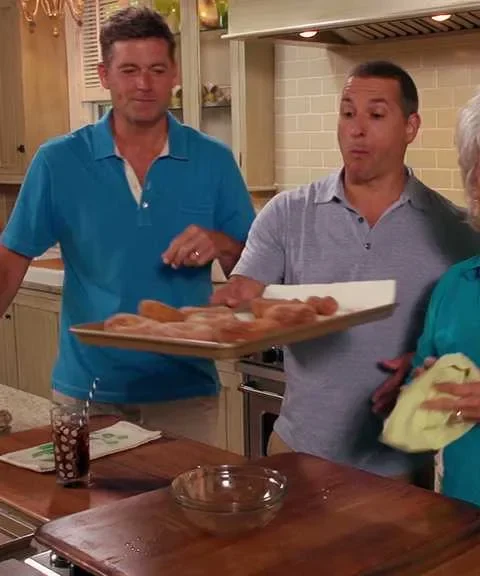 Paula Deen quick donuts on a baking tray being held in a kitchen with a cinnamon sugar bowl on the counter