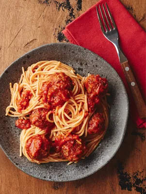 Paula Deen quick spaghetti and meatballs with marinara sauce twirled on a gray plate beside a fork