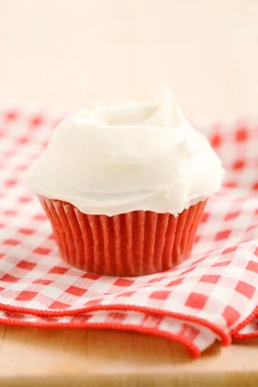 Paula Deen red velvet cupcakes with cream cheese frosting swirled on top, sitting on a red gingham napkin