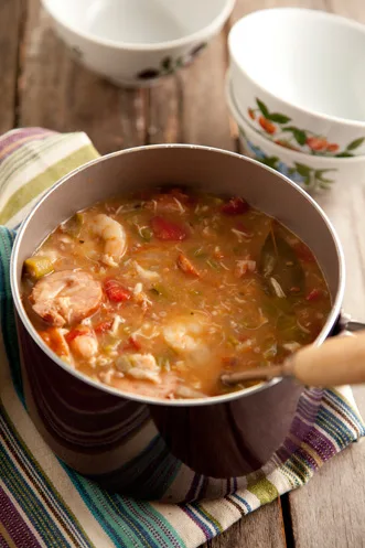Paula Deen Savannah seafood gumbo with shrimp, okra and tomatoes in a pot on a striped towel