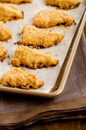 Paula Deen sesame chicken strips baked golden brown with a sesame breadcrumb coating on a parchment-lined baking sheet