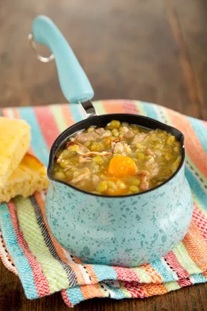 Paula Deen Shaggy Man split pea soup with sausage and carrots in a turquoise enamel pot beside cornbread