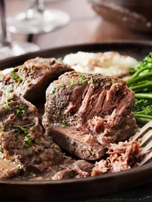 Paula Deen short ribs shredding tender on a dark plate with gravy, mashed potatoes and broccoli