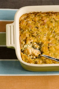Paula Deen shrimp and wild rice casserole baked golden with Cheddar in a cream-colored dish with a serving spoon