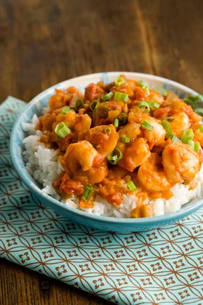 Paula Deen shrimp creole with tender shrimp in tomato sauce over white rice, topped with sliced green onions in a blue bowl