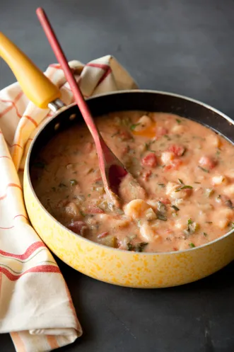 Paula Deen shrimp etouffee in a yellow speckled pan with shrimp, tomatoes and parsley in a creamy roux sauce