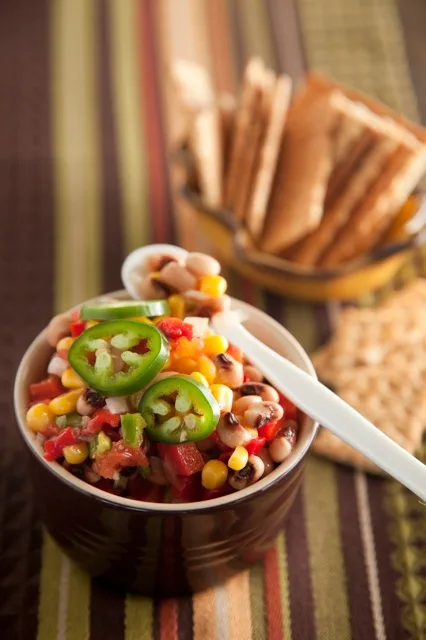 Paula Deen South Georgia Caviar in a brown bowl with black-eyed peas, corn, red pepper and sliced jalapeño, served with crackers