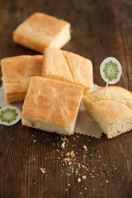 Paula Deen Southern cornbread cut into golden squares on parchment paper on a rustic wooden table